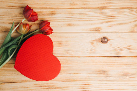 Red bouquet of tulips with red gift box in the shape of heart. Background with a bouquet of flowers. Valentines day gifts. Top viewの写真素材