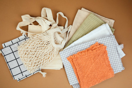 Different texture and colour kitchen towels, waffle and linen and multiple use fabric bags on a brown background. Top viewの写真素材