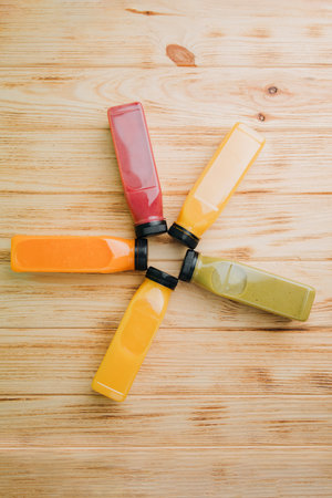 Fruit and vegetable smoothies in transparent plastic bottles. Red, green, orange smoothies on a wooden table. The concept of healthy eating. Top viewの写真素材