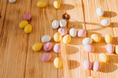 Multi-colored chocolate decorative eggs on a wooden background with sun reflections. Happy Easter background. Top viewの写真素材