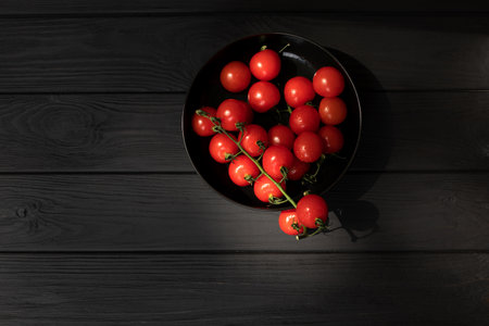Healthy food background. A fresh vegetables, tomatoes in black plate on black wooden background. Flat layの写真素材
