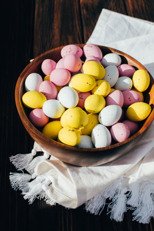 Multi-colored chocolate decorative eggs in wooden plate on a wooden table. Happy Easter background....