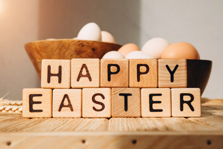 Easter background wit wooden cubes with letters. Chicken eggs on a wooden background with sun...