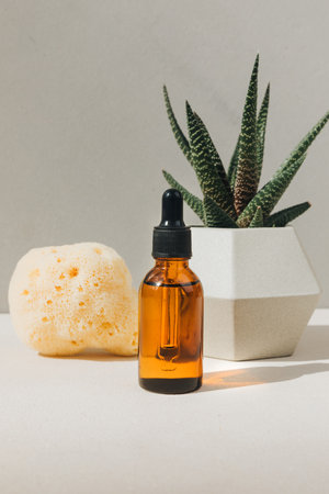 Natural cosmetics. Amber bottle with facial liquid on a concrete background with natural bath sponge and aloe. Front viewの写真素材