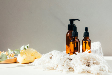 Set of natural cosmetics. Amber bottles with facial, bath liquid on a concrete background with...