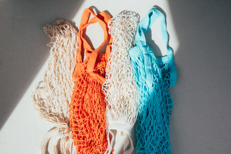 Reusable mesh bags in blue, orange and beige on a concrete background in sunny daylight. Mesh shopping bags. Sustainable use conceptの写真素材