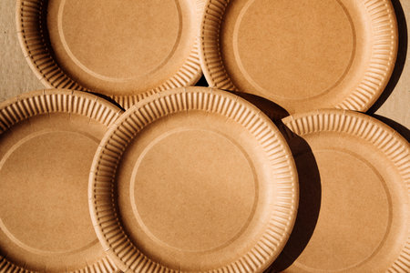 A brown paper plates on a brown cardboard background. Eco friendly, zero waste concept. Top viewの写真素材