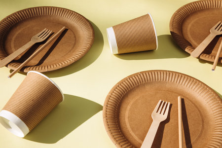 A set of paper utensils and wooden cutlery on a yellow background. Eco friendly, zero waste concept. Top viewの写真素材