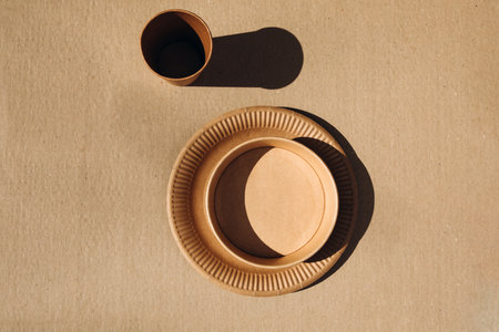 A set of paper utensils, cups and plates, on a brown background. Eco friendly, zero waste concept....