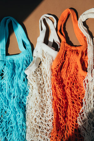 Reusable mesh bags in blue, orange and beige on a brown background in sunny daylight. Mesh shopping bags. Sustainable use conceptの写真素材