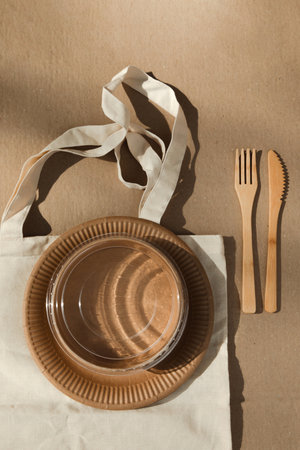 A set of paper utensils and wooden cutlery in fabric bag on a brown background. Eco friendly, zero waste concept. Top viewの写真素材