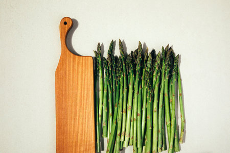 Fresh ripe green asparagus on a concrete background. Harvest asparagus, bunches and wooden tray. Healthy eating concept. Top viewの写真素材