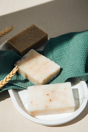 Handmade soap from natural ingredients, various herbs, lavender. Concept of sustainable use, bath product on green towel. Top viewの写真素材