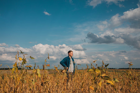 Farmer, agronomist in the soybean field. Controlling the growth of agricultural crops. Green soy with beans. Front viewの写真素材