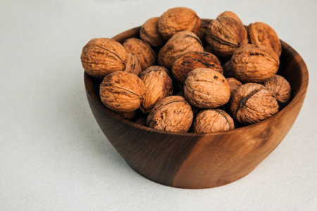 Unpeeled walnuts in a wooden bowl on a gray background. Autumn background. Top viewの写真素材