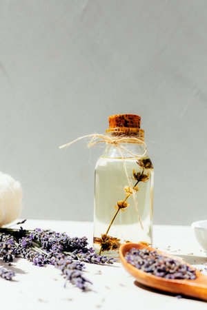 Lavender oil on light background with lavender flowers in a bright sunlight. Front viewの写真素材