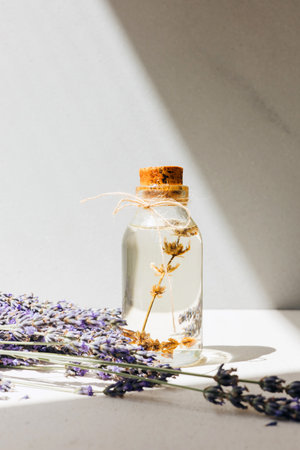 Lavender oil on light background with lavender flowers in a bright sunlight. Front viewの写真素材