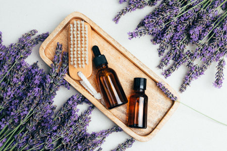 Set of natural cosmetics. Amber bottles with facial, bath liquid on wooden tray on a concrete background with lavender flowers. Top viewの写真素材