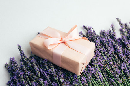 Background for greetings. Gift wrapping in soft pink paper with lavender flowers. Top viewの写真素材