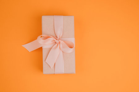 Greeting background. Gift wrapping in soft pink paper on a orange background with copy space. Top viewの写真素材