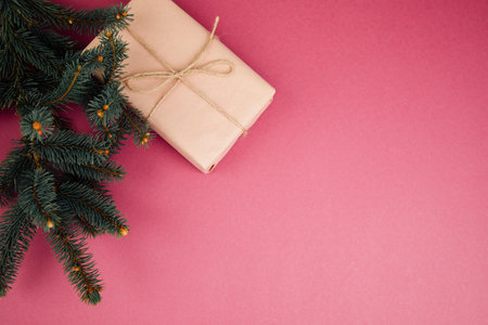 Christmas, festive background. Rose gift box with brown ribon on green coniferous branches on a bright pink background. Top viewの写真素材