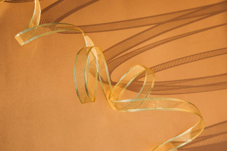 Golden festival tinsel and shadows on a yellow background. Top view