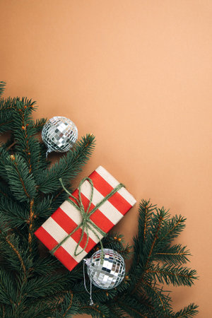 Christmas, festive background. Brown and red gift box on green coniferous branches on a brown background. Top viewの写真素材