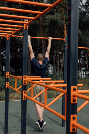 Outdoor sports. A man doing exercises on a sports ground in summer morning. Healthy lifestyle concept. Front viewの写真素材