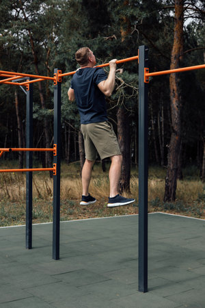 Outdoor sports. A man doing exercises on a sports ground in summer morning. Healthy lifestyle concept. Front viewの写真素材
