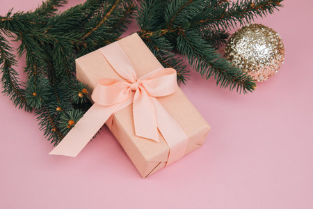 Christmas, festive background. Rose gift box with pink ribon on green coniferous branches on a pink background. Top viewの写真素材