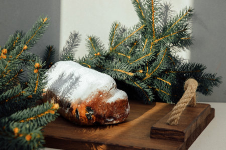 Christmas stollen on a wooden board with green branches of a Christmas tree. Christmas background, Christmas dessertsの写真素材