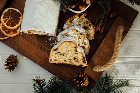 Christmas stollen on a wooden board with green branches of a Christmas tree on white wooden background. Christmas background, Christmas dessertsの写真素材