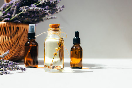 Lavender oil on light background with lavender flowers in a bright sunlight. Front viewの写真素材