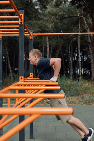 Outdoor sports. A man doing exercises on a sports ground in summer morning. Healthy lifestyle concept. Front viewの写真素材