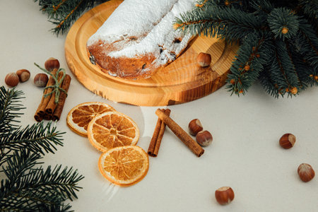 Christmas stollen on a wooden board with green branches of a Christmas tree on dark wooden background. Christmas background, Christmas dessertsの写真素材