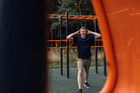 A man doing exercises on a sports ground in summer morning. Healthy lifestyle concept. Front view
