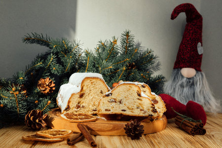 Christmas stollen on a wooden board with green branches of a Christmas tree on wooden background. Christmas background, Christmas dessertsの写真素材
