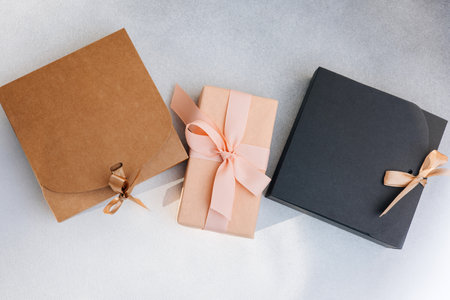 Greeting background. Brown, black and pink gift boxes on a gray background with copy space. Top view
