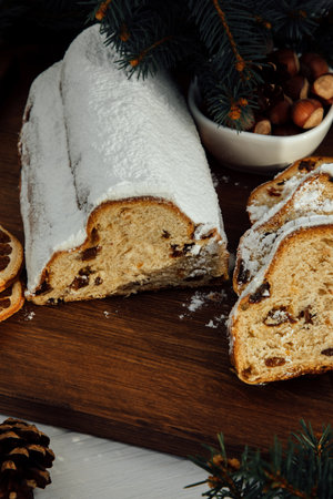 Christmas stollen on a wooden board with green branches of a Christmas tree. Christmas background, Christmas dessertsの写真素材