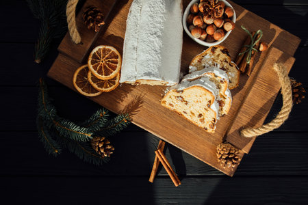 Christmas stollen on a wooden board with green branches of a Christmas tree. Christmas background, Christmas dessertsの写真素材