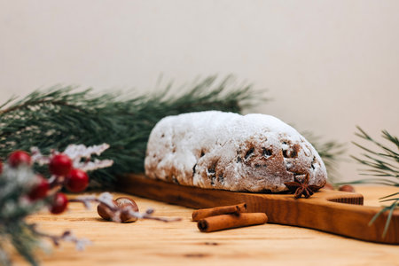 Christmas stollen in powdered sugar on a light background with pine branches and tangerines. Traditional Christmas delicacies. Front viewの写真素材