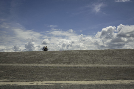 The Netherlands. - June 20, 2015: A couple of bicyclists moves on horizon under the cloudsのeditorial素材