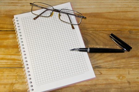 Notebook with glasses and fountain pen on the wooden deskの写真素材
