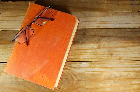 Close old book with glasses on the wooden backgroundの写真素材