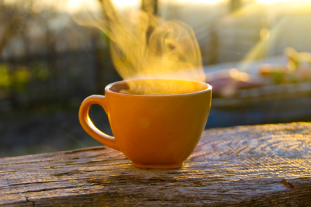 Morning cup of coffee on wooden table at sunriseの写真素材