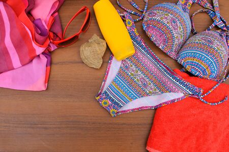 Set of beachwear on wooden background. Top view of swimsuit, towel, pareo, sunscreen and sunglasses. Summer vacation conceptの写真素材