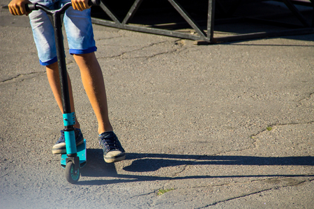 Boy on kick scooter in city parkの写真素材