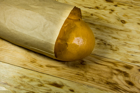 Bread packed in paper on wooden table