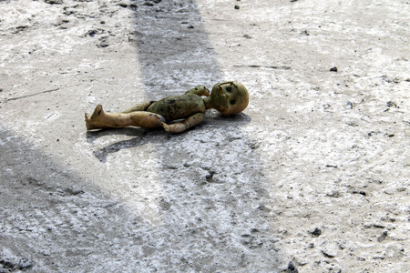 Abandoned old broken doll on grey concrete floorの写真素材