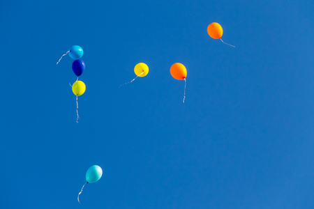 Colorful balloons flying in the blue skyの写真素材